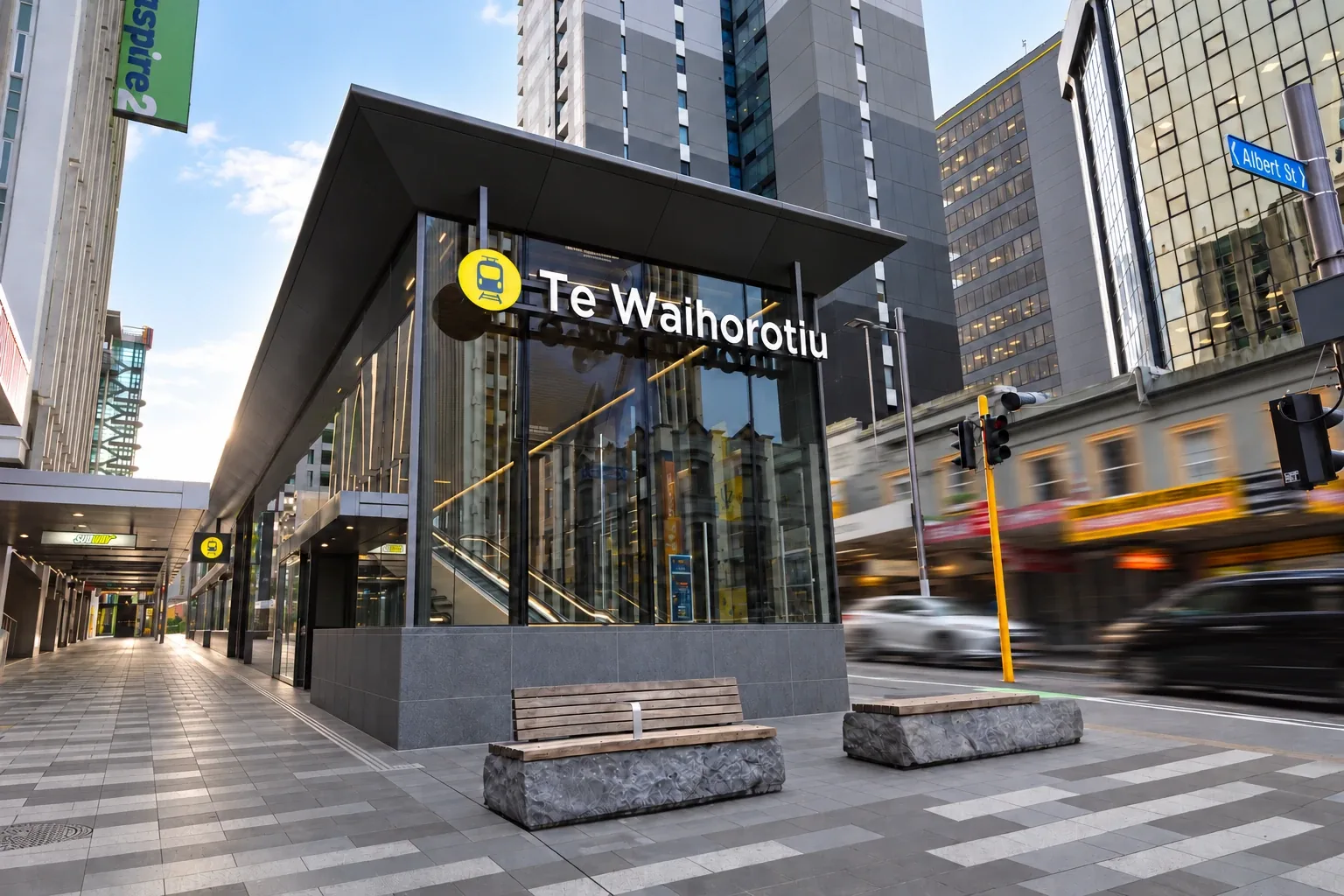 The Te Waihorotiu train station entrance on Albert Street, Auckland, with the Aspire2 sign on our campus building behind it