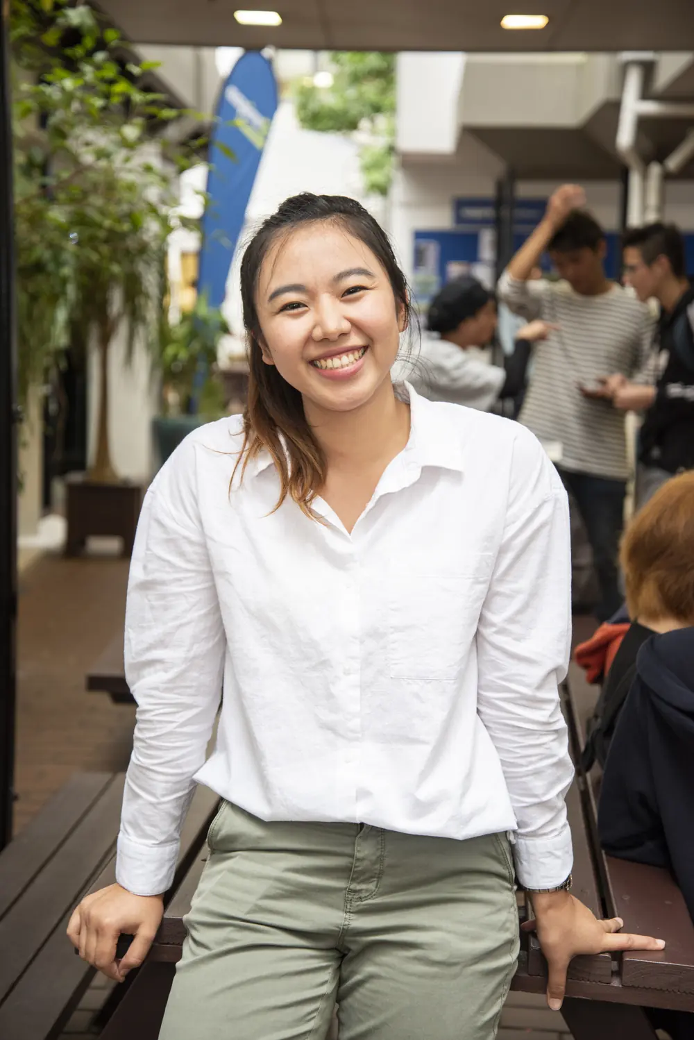 A smiling student sitting on a bench in the campus courtyard