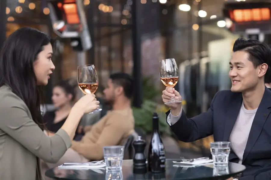 Two friends raising a glass at an outdoor restaurant in Britomart